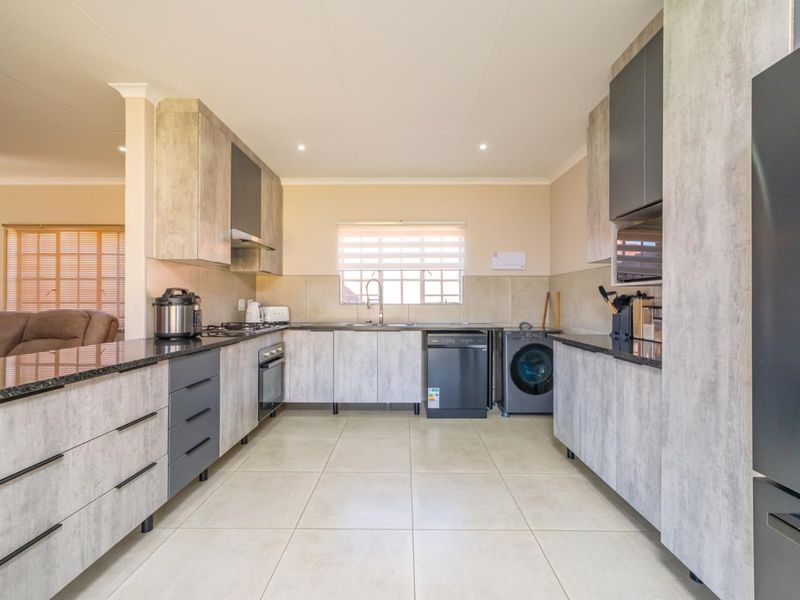 Modern kitchen featuring contemporary grey cabinetry, granite countertops, integrated appliances, and tiled flooring, offering a clean and functional workspace.