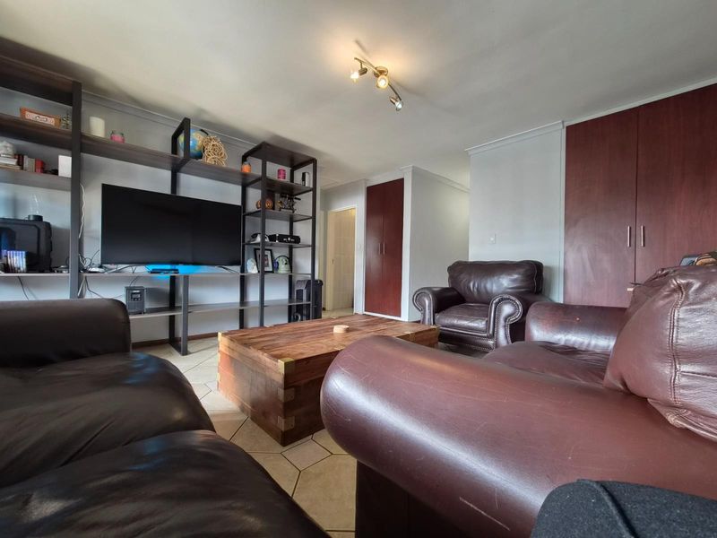 A living room featuring tiled flooring, built-in storage cupboards, and a ceiling-mounted spotlight fixture.