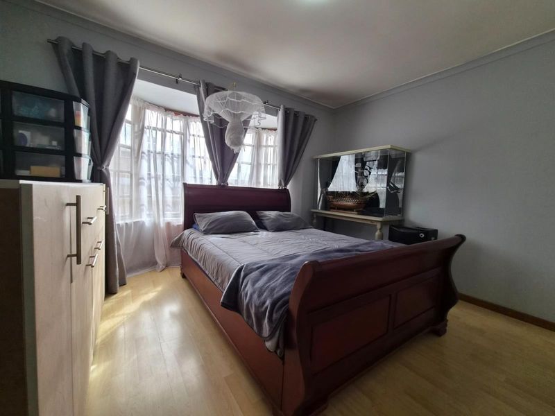 A bedroom featuring laminate flooring and a bay window that allows for natural light.
