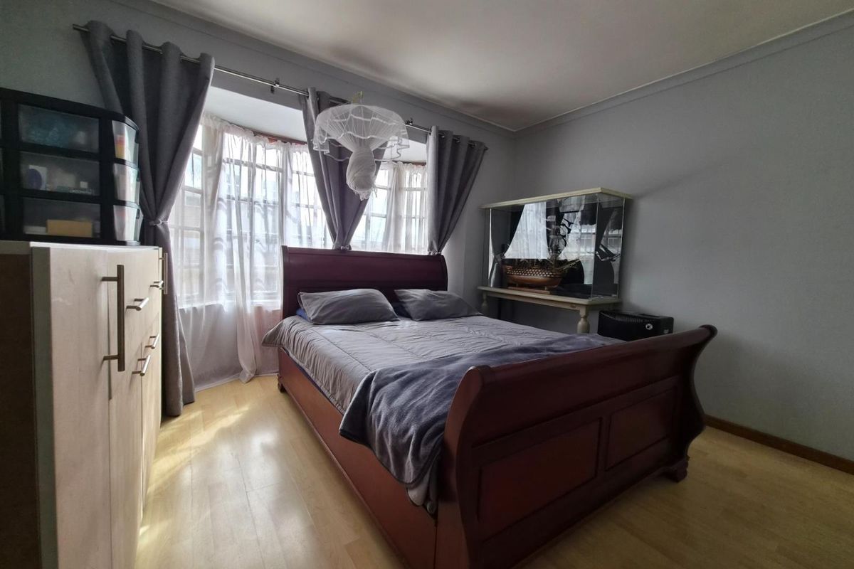A bedroom featuring laminate flooring and a bay window that allows for natural light.