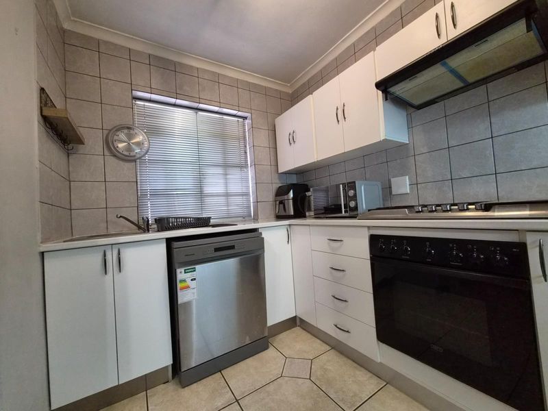 A functional kitchen featuring white cabinetry, tiled backsplash, built-in oven with gas hob, extractor fan, and tiled flooring.