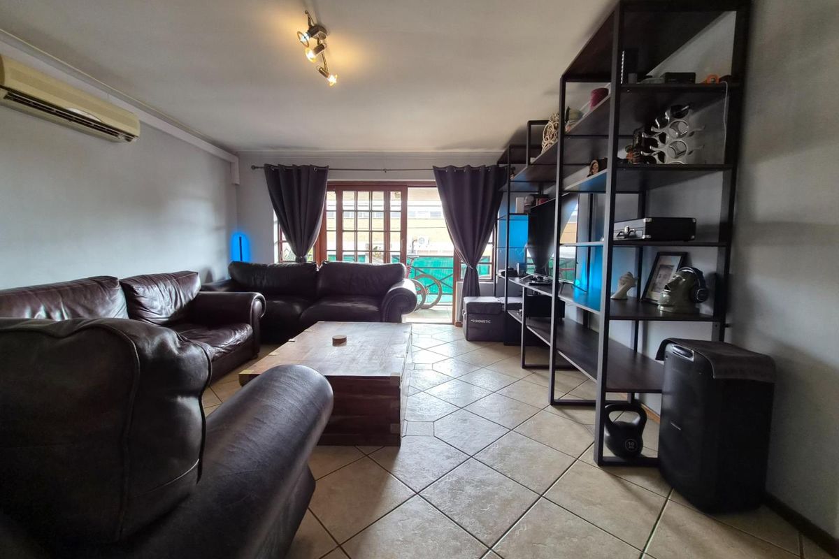 Spacious living room featuring tiled flooring, a wall-mounted air conditioning unit, and direct access to an outdoor area through sliding glass doors.