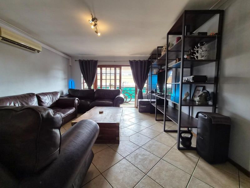 Spacious living room featuring tiled flooring, a wall-mounted air conditioning unit, and direct access to an outdoor area through sliding glass doors.