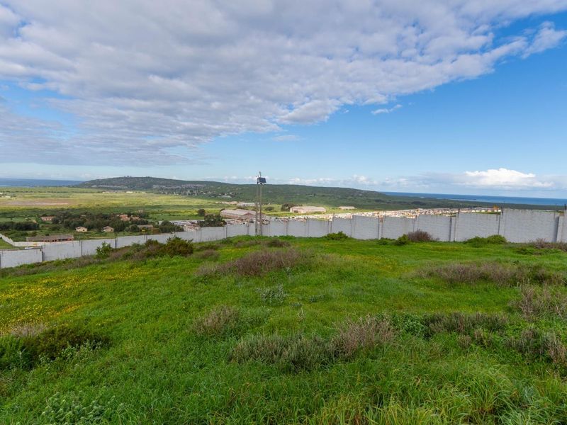 Elevated view overlooking a vacant residential plot with a perimeter wall and electric fencing, featuring expansive coastal and landscape vistas.