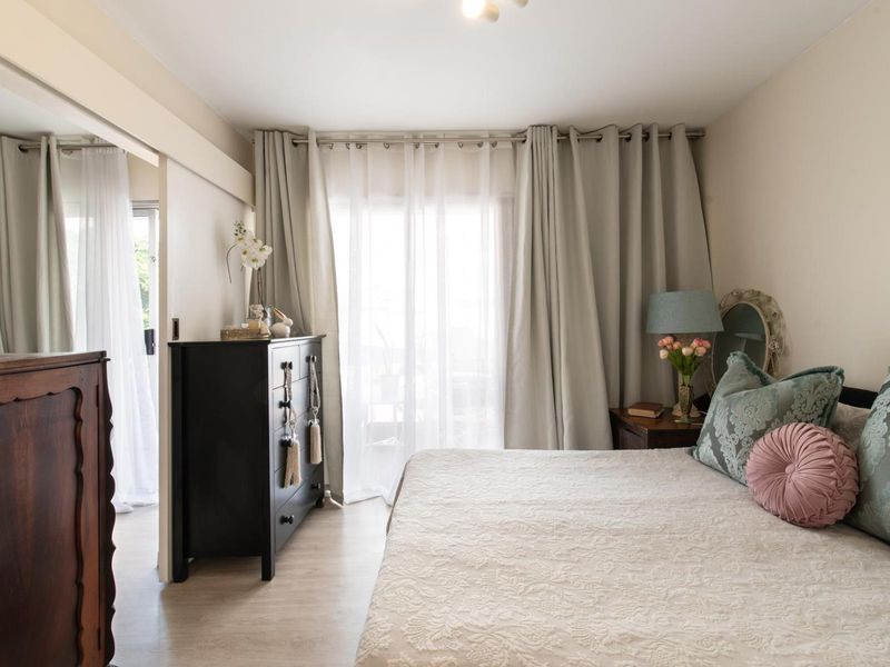 A well-lit bedroom featuring laminate flooring, a built-in wardrobe, and a sliding door providing access to an outdoor area.