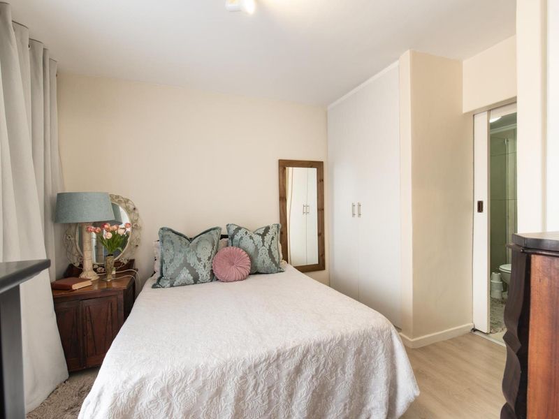 A well-maintained bedroom featuring laminate flooring, a built-in wardrobe, and direct access to an en-suite bathroom.