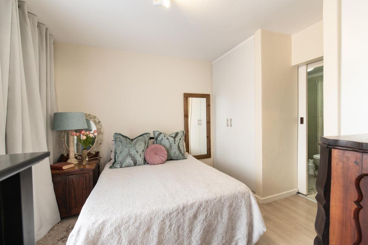 A well-maintained bedroom featuring laminate flooring, a built-in wardrobe, and direct access to an en-suite bathroom.
