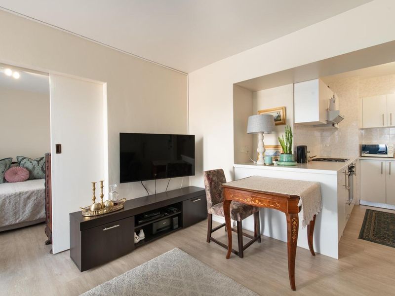 Open-plan living area featuring a compact kitchen with built-in cabinetry, hob, and oven, seamlessly connected to the main living space.