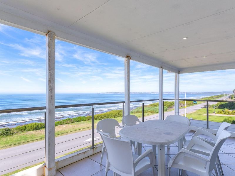 Spacious covered balcony featuring tiled flooring and a stainless steel balustrade, offering expansive ocean views and potential for outdoor entertainment.