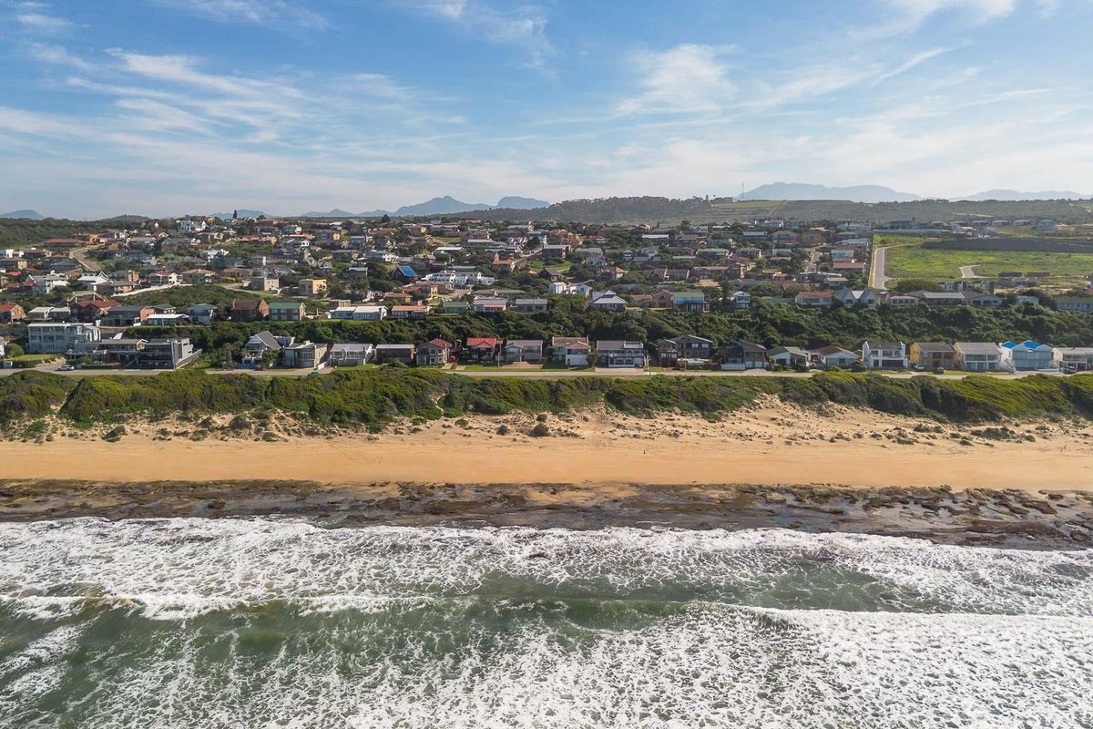 An aerial view of a coastal residential neighborhood situated along a sandy beach and rocky shoreline.