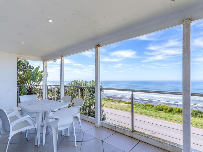 Spacious covered balcony featuring tiled flooring and stainless steel balustrades, offering expansive ocean views.
