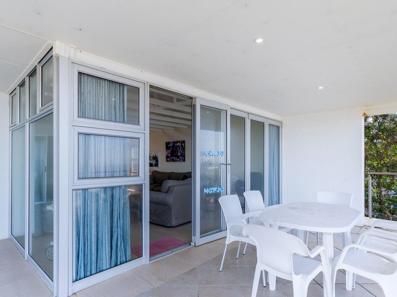 A covered patio area featuring aluminium sliding doors, tiled flooring, and recessed lighting, providing a functional outdoor space for relaxation.