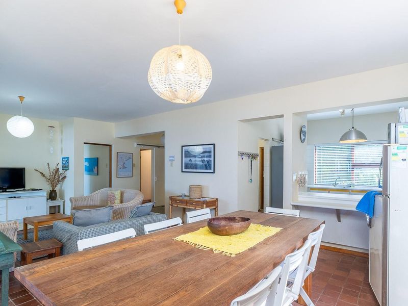 Open-plan living and dining area featuring terracotta flooring, pendant lighting, and a convenient pass-through window connecting to the kitchen space.