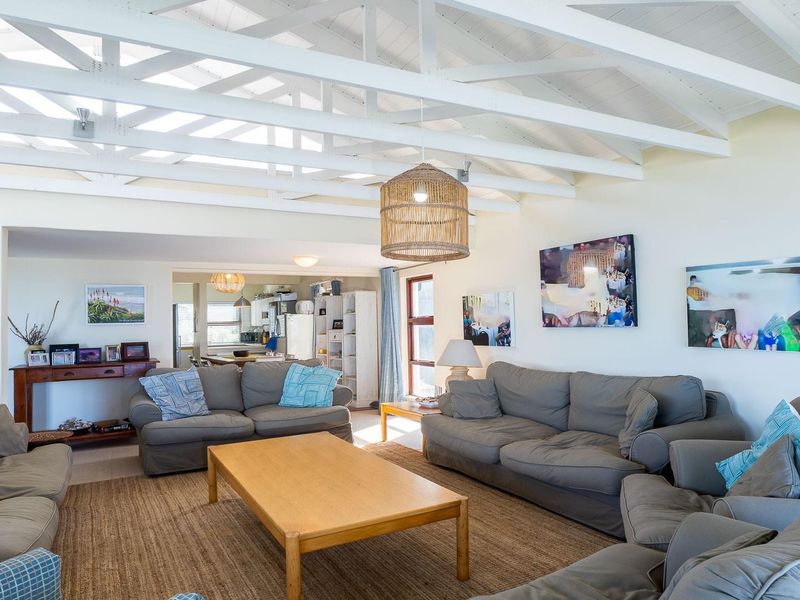Spacious open-plan living area featuring a high vaulted ceiling with exposed timber beams, flowing seamlessly into a functional kitchen space.
