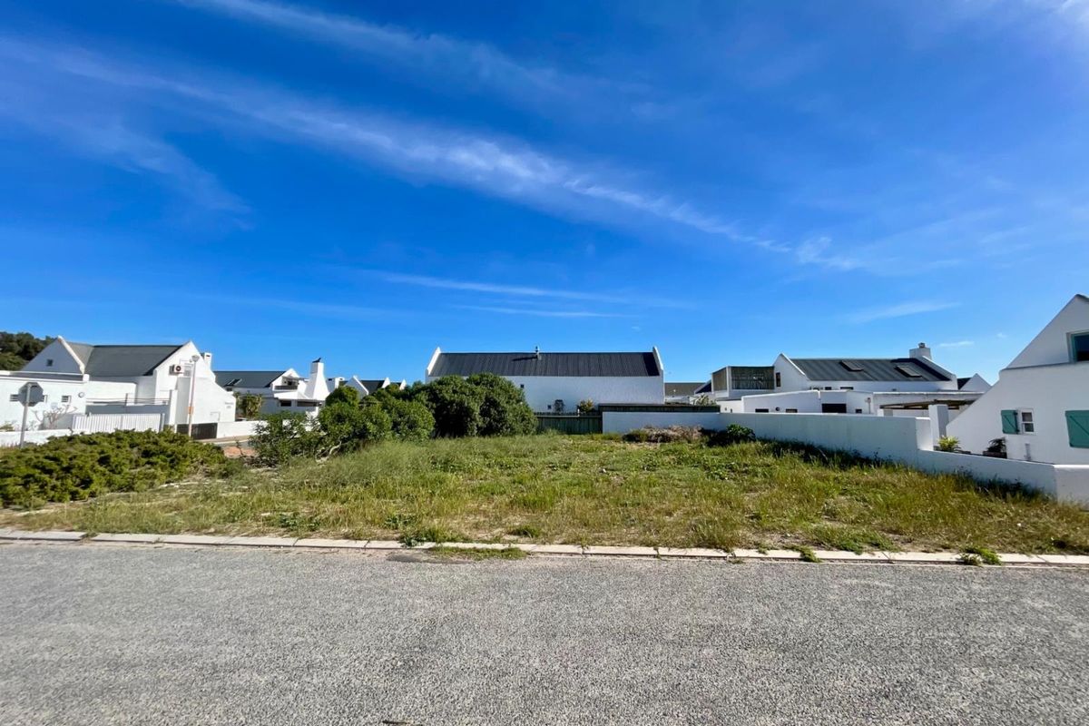 A vacant residential plot situated in a developed estate, featuring boundary walls and street-level access, ready for new construction.