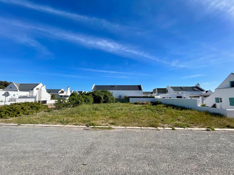 A vacant residential plot situated in a developed estate, featuring boundary walls and street-level access, ready for new construction.