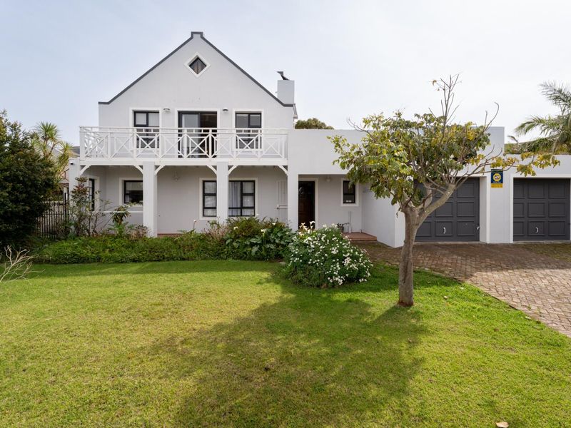 A well-maintained double-story home featuring a paved driveway, double garage, and a spacious upper-level balcony overlooking a neat front garden.