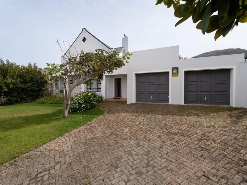 Front view of a residential property featuring a double garage, paved driveway, and a well-maintained garden area.