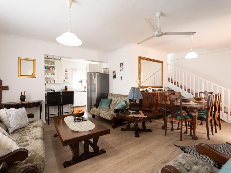 Spacious open-plan living and dining area featuring laminate flooring, a central staircase, and a functional kitchen with a breakfast bar.