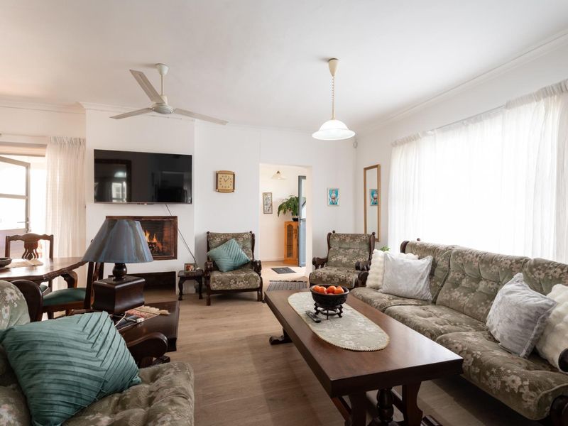 A spacious living room featuring a built-in fireplace, ceiling fan, and light-toned laminate flooring, offering a comfortable and functional layout.