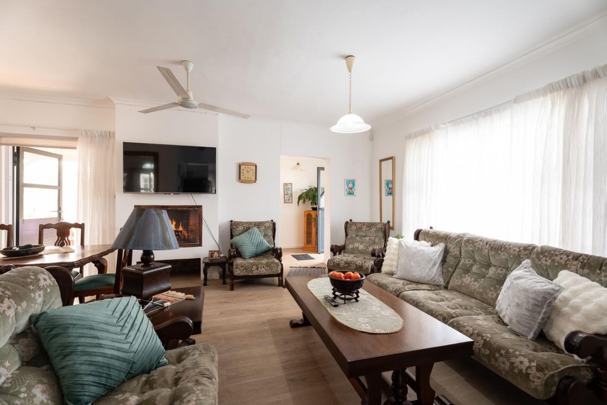 A spacious living room featuring a built-in fireplace, ceiling fan, and light-toned laminate flooring, offering a comfortable and functional layout.