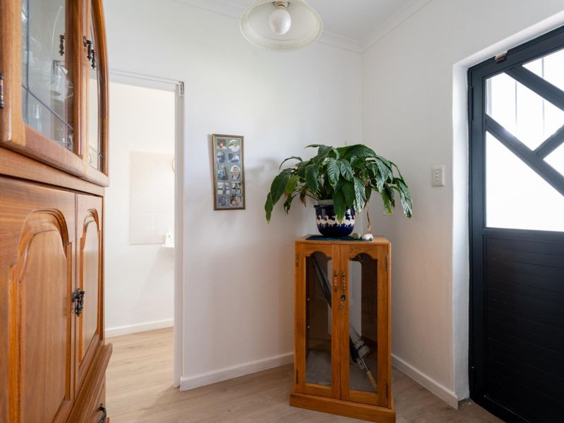 A bright entry area featuring laminate flooring, a modern security gate, and a neutral color palette.