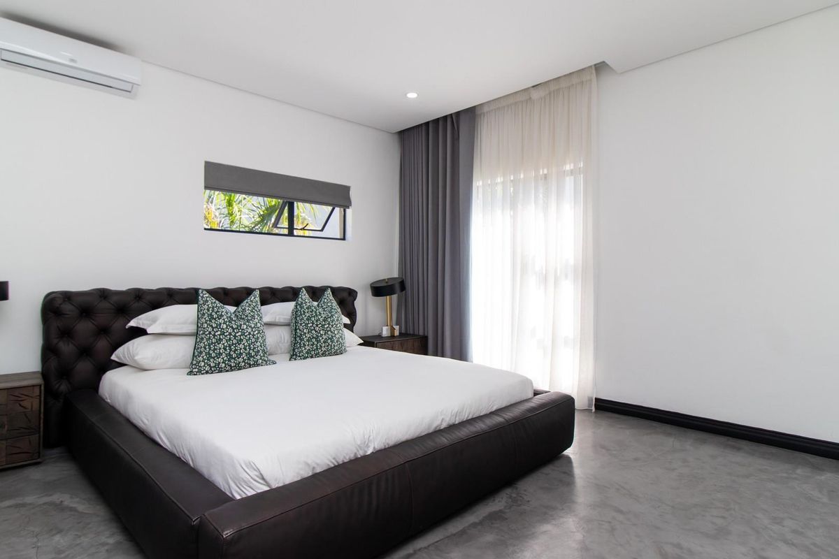 Modern bedroom featuring polished concrete floors, split-system air conditioning, and floor-to-ceiling curtains.