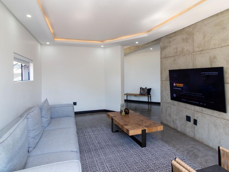 Modern living room featuring a polished concrete floor, a striking concrete feature wall, and recessed ceiling lighting.