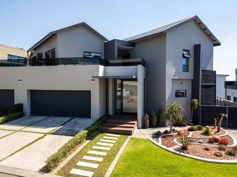 Modern double-story residential home featuring a contemporary facade, double garage, paved driveway, and a well-maintained landscaped front garden.