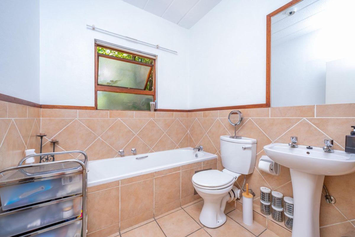 A functional bathroom featuring a bathtub, pedestal sink, and toilet with neutral-toned wall and floor tiling.