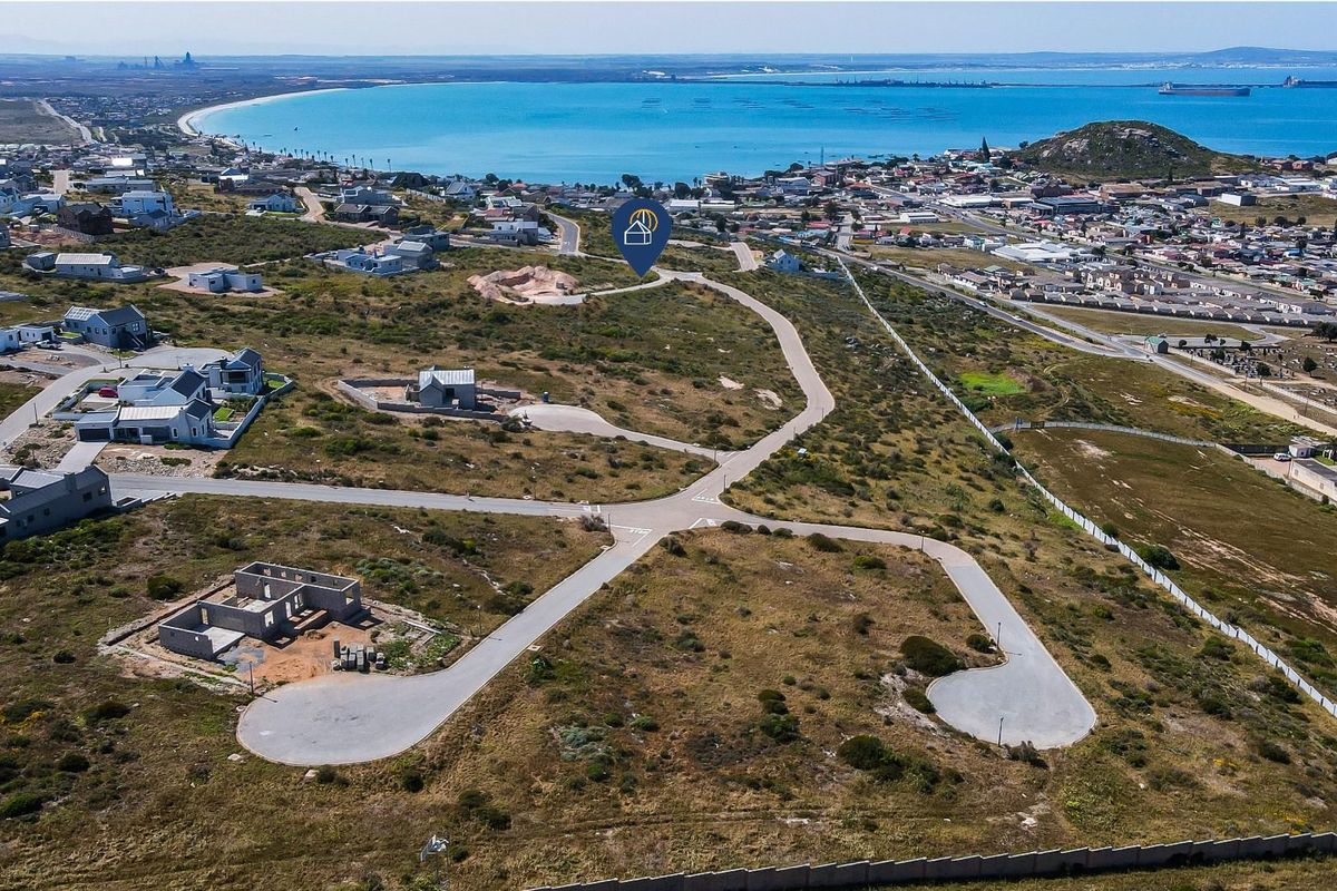 Aerial view of a residential vacant land development featuring paved roads and proximity to the coastline.