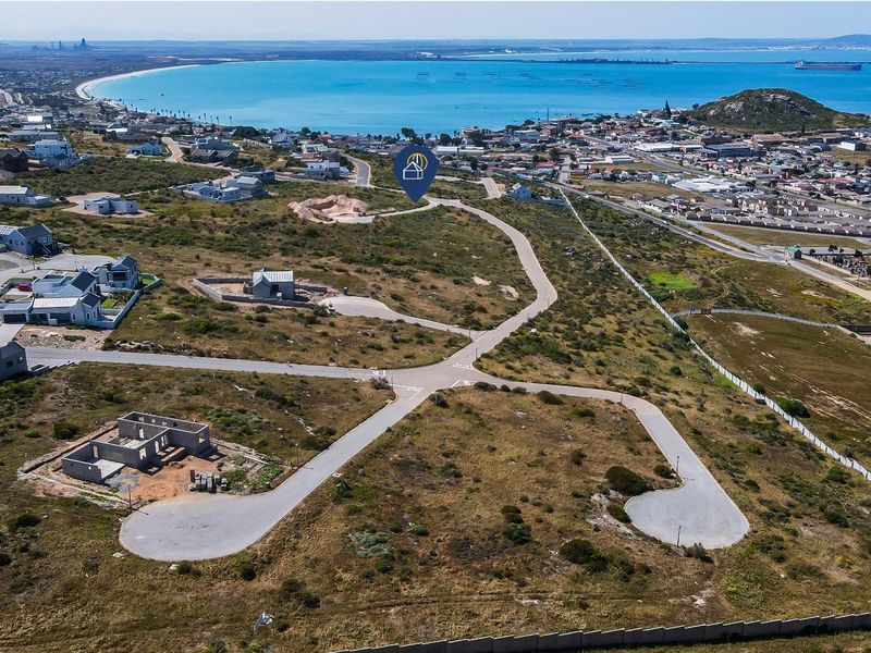 Aerial view of a residential vacant land development featuring paved roads and proximity to the coastline.