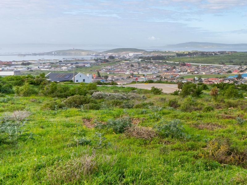 A scenic elevated view overlooking the surrounding coastal town, landscape, and distant bay, showcasing the natural terrain of the vacant residential land.