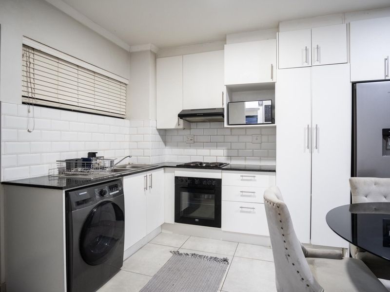 Modern kitchen featuring white cabinetry, granite countertops, subway tile backsplash, and integrated appliances including an oven, hob, and extractor fan.