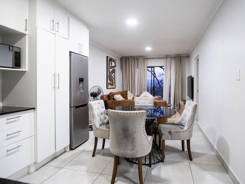An open-plan living and dining area featuring modern white cabinetry, tiled flooring, and a sliding glass door leading to an outdoor space.