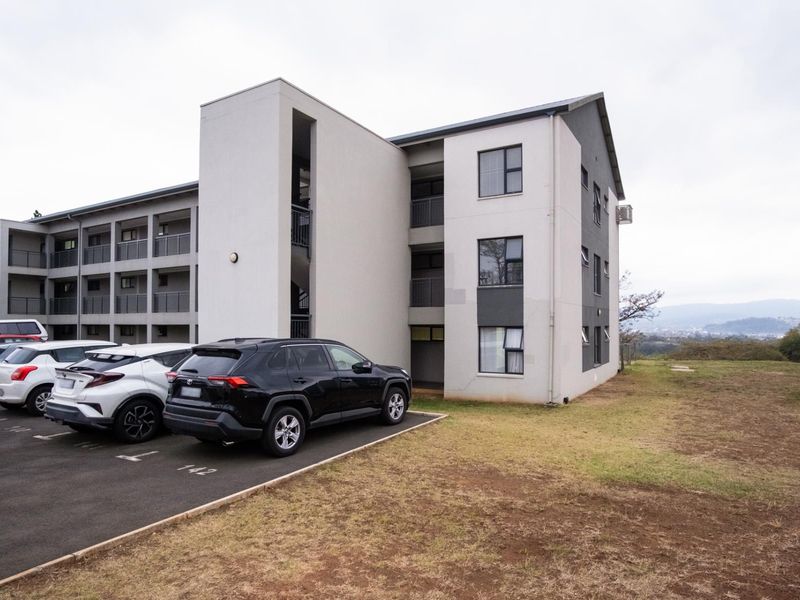 Exterior view of a multi-story apartment building featuring a dedicated parking area and modern facade design.
