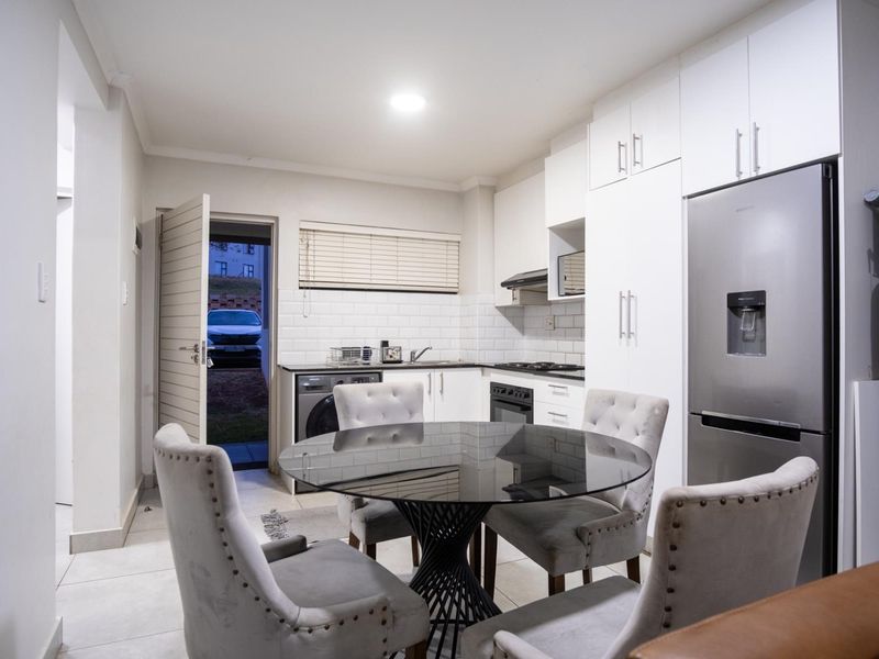 Modern kitchen featuring white cabinetry, subway tile backsplash, built-in oven, hob, and extractor fan, with direct access to the exterior.