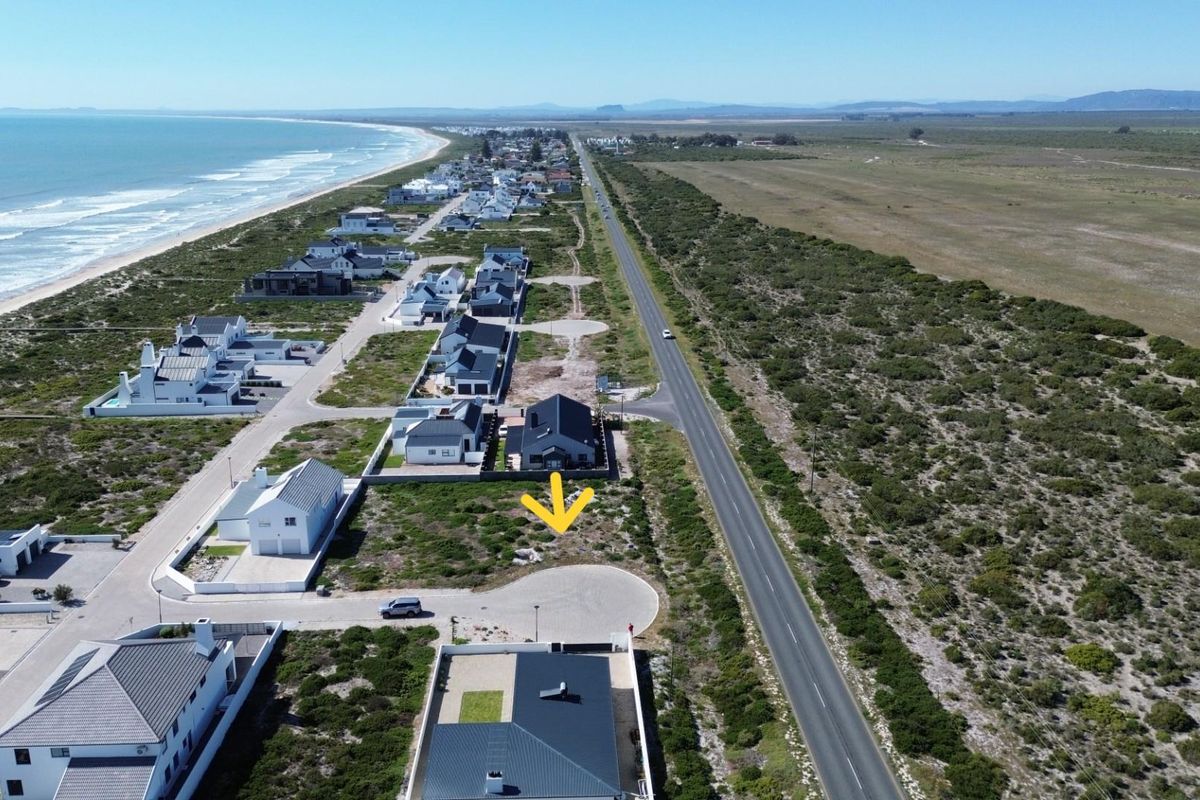Aerial view of a vacant residential plot situated in a coastal development, offering proximity to the beach and main road access.