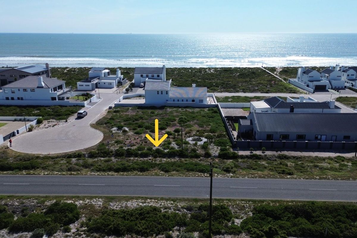 Aerial view of a vacant residential plot situated in a coastal estate, offering proximity to the ocean and established neighborhood infrastructure.