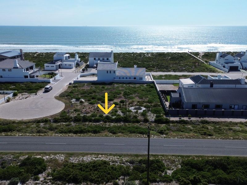 Aerial view of a vacant residential plot situated in a coastal estate, offering proximity to the ocean and established neighborhood infrastructure.