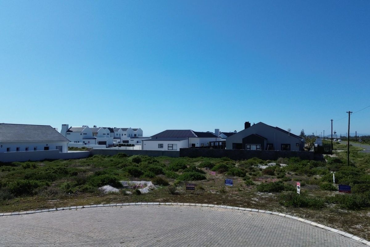 An aerial view of a vacant residential plot situated in a developed estate, featuring a paved cul-de-sac and surrounding established homes.