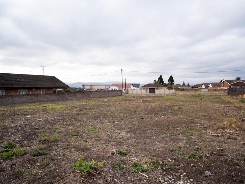 A vacant residential plot of land featuring a level surface, boundary wall, and surrounding neighborhood views, ready for development.