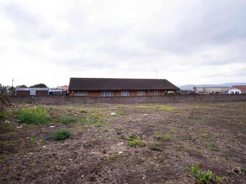 A vacant residential plot of land featuring a boundary wall and wire fencing, offering a clear view of the surrounding neighborhood.