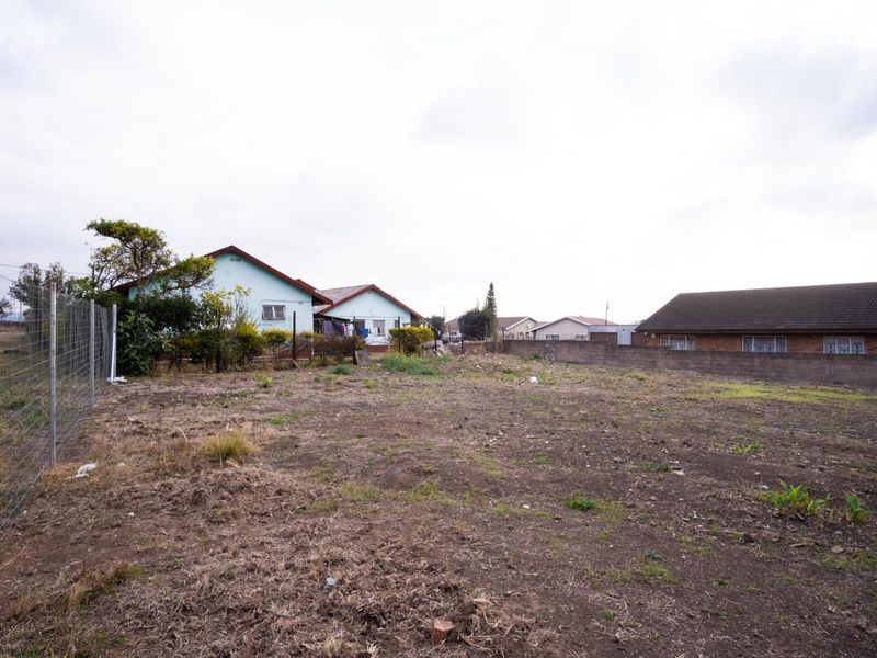A vacant residential plot featuring wire mesh fencing and a concrete block boundary wall, offering a clear space for potential development.