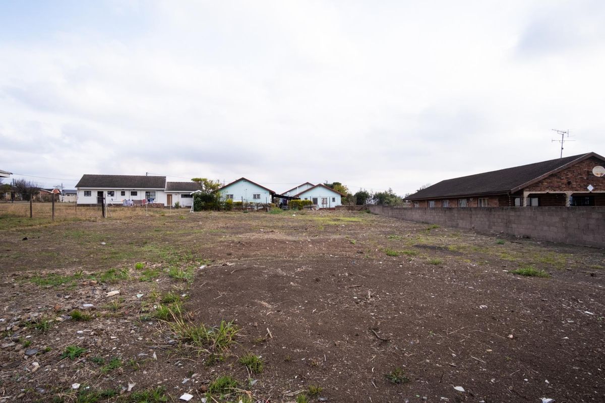 A vacant residential plot of land featuring perimeter walling and fencing, situated in a developed neighborhood setting.