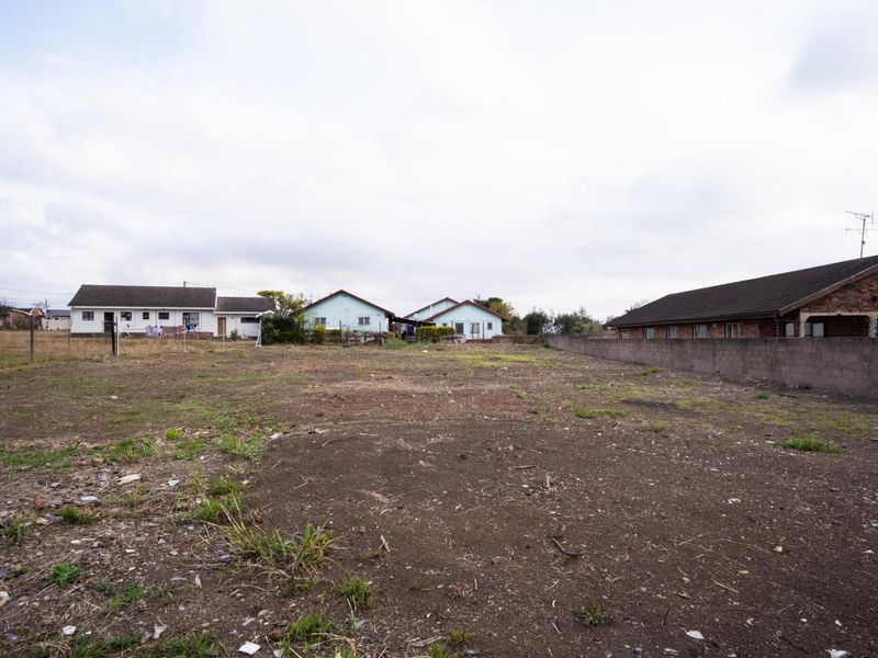 A vacant residential plot of land featuring perimeter walling and fencing, situated in a developed neighborhood setting.