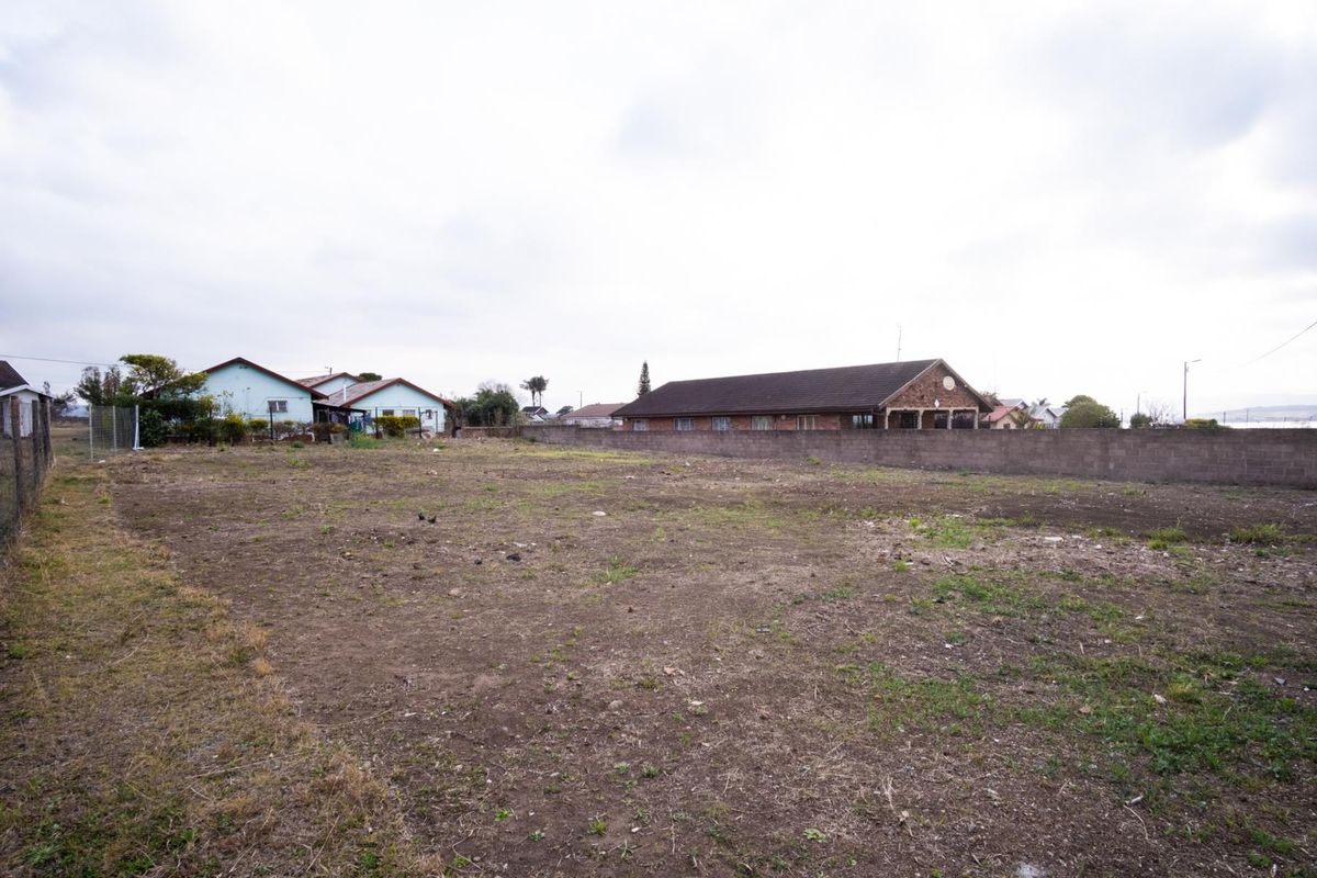 A vacant residential plot of land featuring a perimeter boundary wall and surrounding residential neighborhood views.