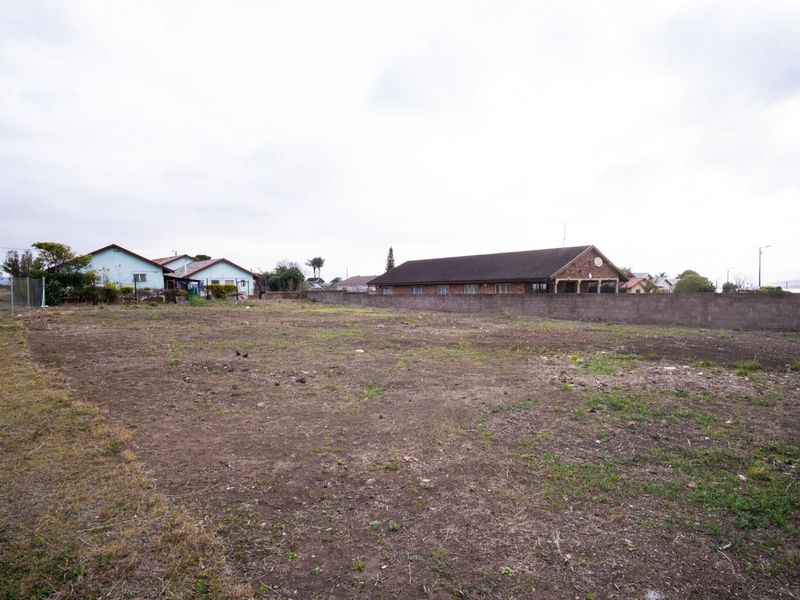 A vacant residential plot of land featuring a perimeter boundary wall and surrounding residential neighborhood views.