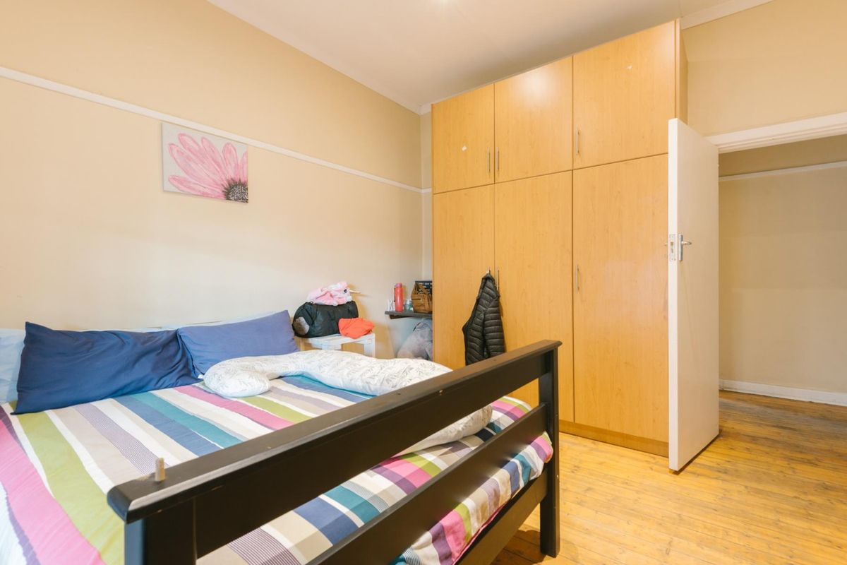 A bedroom featuring built-in wooden cupboards, classic picture rails, and original wooden flooring.