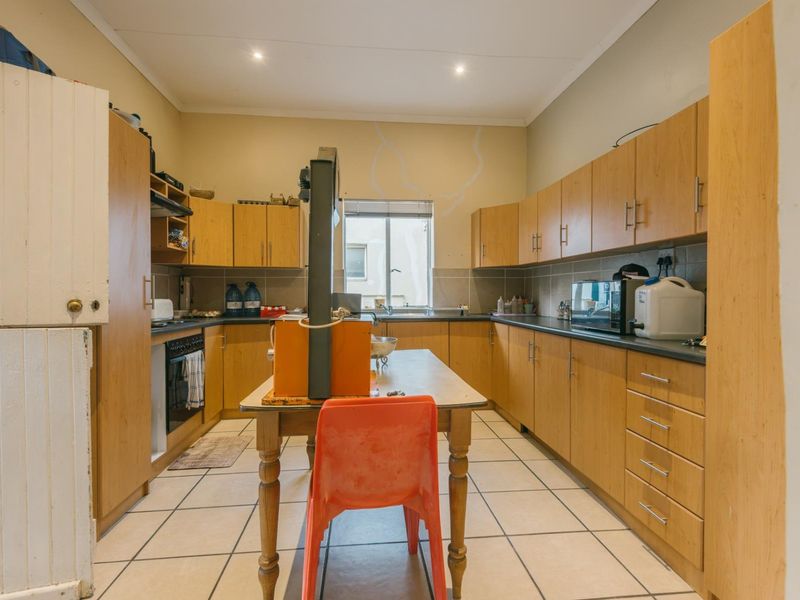 Functional kitchen featuring laminate cabinetry, tiled flooring, built-in oven, and ample counter space, offering a practical layout with potential for modern updates.